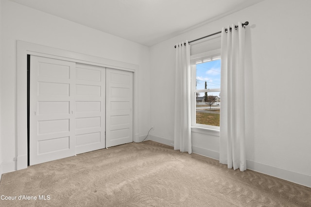 unfurnished bedroom with a closet, baseboards, and light colored carpet