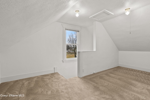 bonus room with carpet flooring, a textured ceiling, attic access, and lofted ceiling