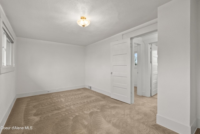 unfurnished room featuring a healthy amount of sunlight, baseboards, carpet floors, and a textured ceiling