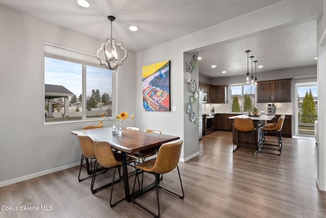 dining room featuring a textured ceiling, recessed lighting, baseboards, light wood-type flooring, and an inviting chandelier