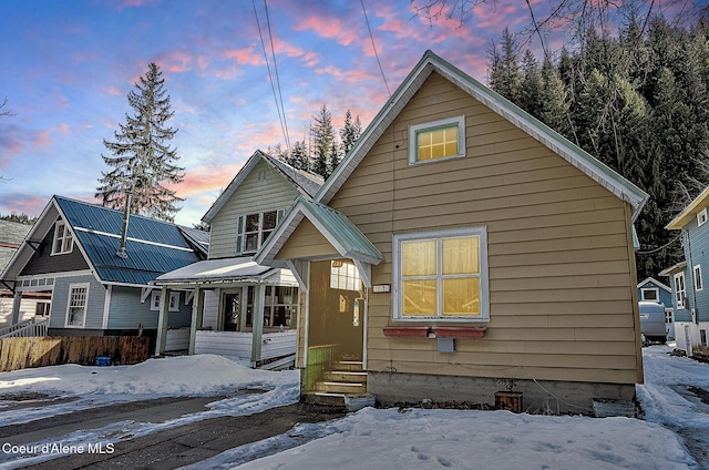 snow covered house with metal roof and a porch