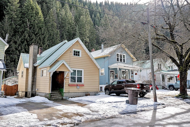 view of front of home featuring entry steps, a chimney, and a forest view