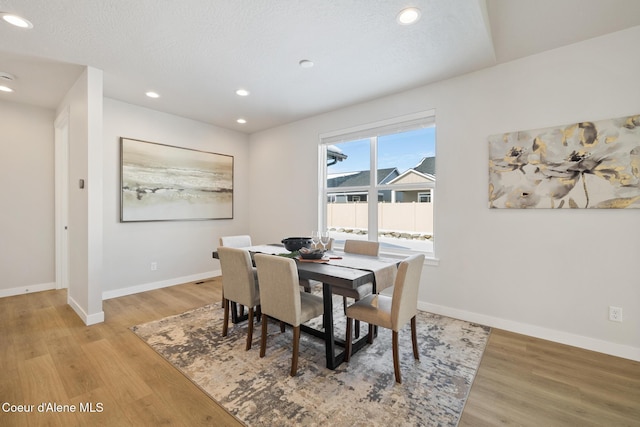 dining space featuring a textured ceiling, recessed lighting, light wood-type flooring, and baseboards