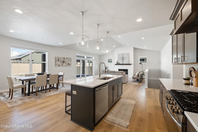 kitchen featuring lofted ceiling, stainless steel appliances, a sink, and light countertops