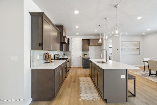 kitchen with tasteful backsplash, a sink, stainless steel range with gas stovetop, and light wood-style floors