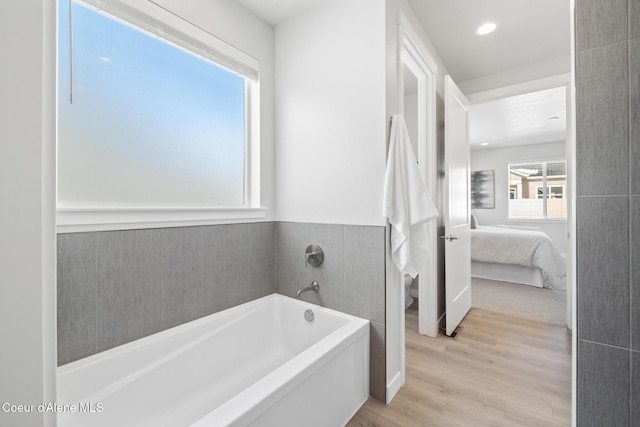 ensuite bathroom with recessed lighting, wood finished floors, a bath, and connected bathroom