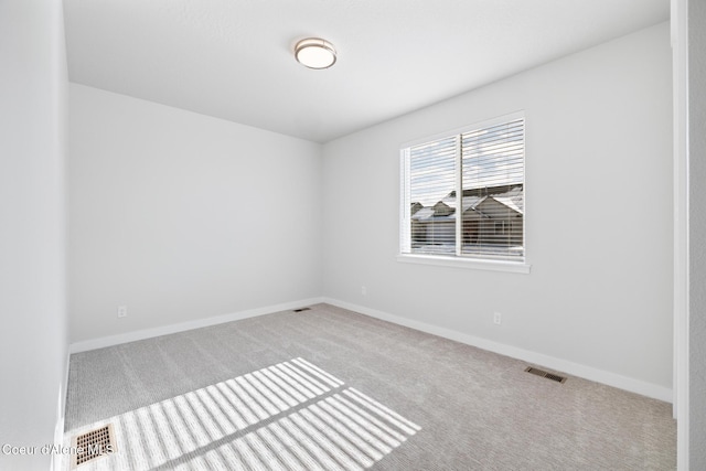 carpeted spare room featuring visible vents and baseboards