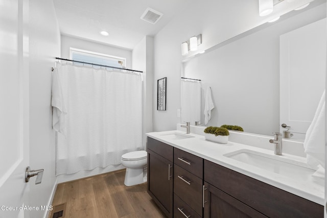 bathroom with toilet, visible vents, a sink, and wood finished floors