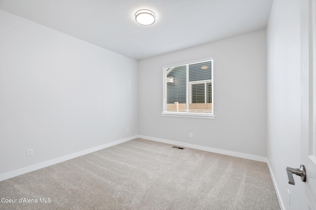 spare room featuring carpet, visible vents, and baseboards