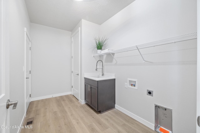 clothes washing area with washer hookup, light wood-style floors, a sink, electric dryer hookup, and baseboards