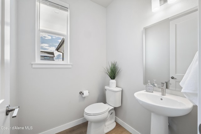 half bath featuring toilet, baseboards, and wood finished floors