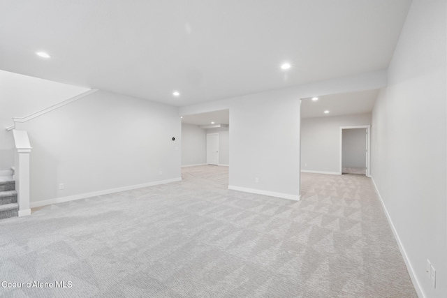 finished basement with light carpet, baseboards, stairway, and recessed lighting