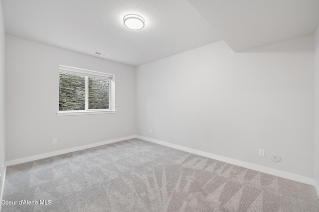 carpeted empty room featuring a textured ceiling, visible vents, and baseboards