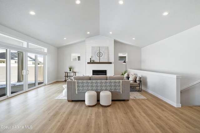 living room with lofted ceiling, a fireplace, light wood-style flooring, and baseboards