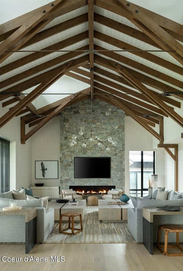 unfurnished living room with high vaulted ceiling, a fireplace, beamed ceiling, and light wood finished floors