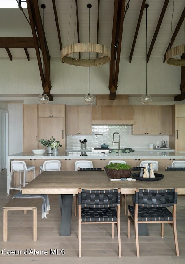 kitchen with high vaulted ceiling, light countertops, decorative backsplash, and decorative light fixtures