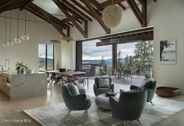 sitting room with high vaulted ceiling, beamed ceiling, light wood-type flooring, and a healthy amount of sunlight