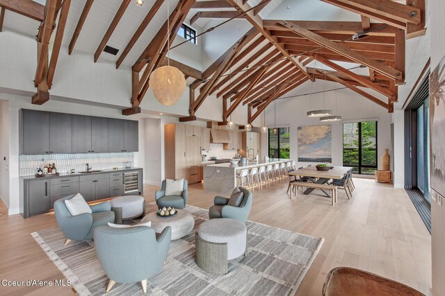 6895 S Gozzer Rd Unit A201, Harrison, ID 83833 - living area featuring wine cooler, high vaulted ceiling, light wood-style flooring, beam ceiling, and a chandelier