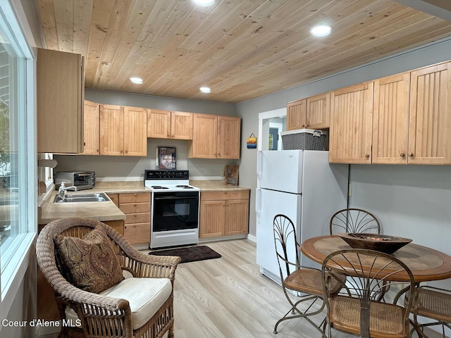 kitchen with electric stove, recessed lighting, light countertops, light brown cabinetry, and freestanding refrigerator