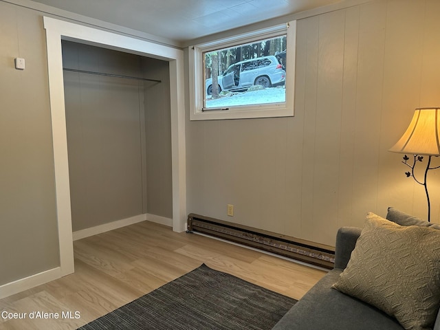 unfurnished bedroom featuring light wood-style floors, a baseboard radiator, a closet, and baseboards