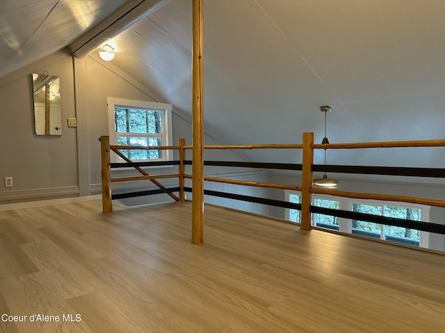 additional living space featuring vaulted ceiling with beams and wood finished floors