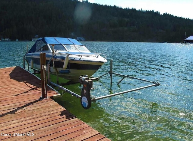 view of dock with a water view and a wooded view