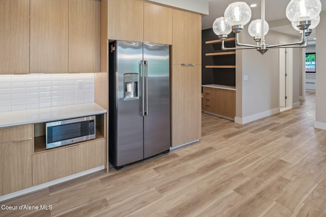 kitchen with stainless steel appliances, light countertops, hanging light fixtures, and modern cabinets