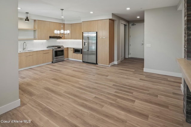 kitchen featuring stainless steel appliances, light countertops, light brown cabinetry, open shelves, and pendant lighting