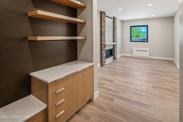 unfurnished living room featuring light wood-style flooring, a fireplace, baseboards, and recessed lighting