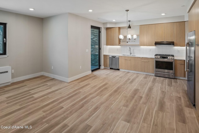 kitchen with light countertops, appliances with stainless steel finishes, a sink, and under cabinet range hood