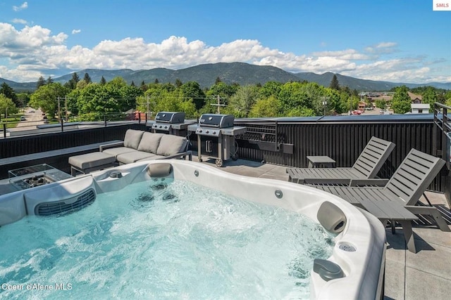 view of pool with outdoor lounge area, a grill, a mountain view, and a hot tub