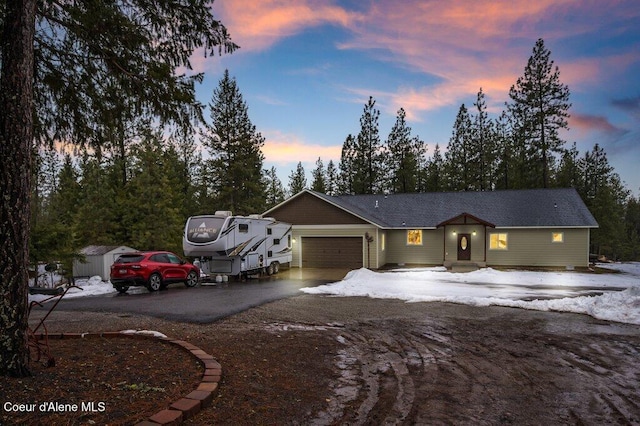 view of front of property with driveway, a storage shed, and an attached garage