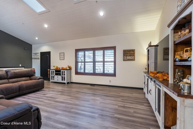 living room with lofted ceiling with skylight, baseboards, wood finished floors, and recessed lighting