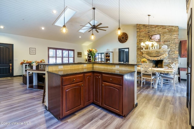 kitchen with light wood-style floors, pendant lighting, lofted ceiling with skylight, and a kitchen breakfast bar