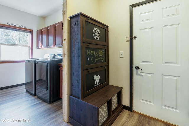 clothes washing area featuring baseboards, light wood finished floors, cabinet space, and washer and dryer