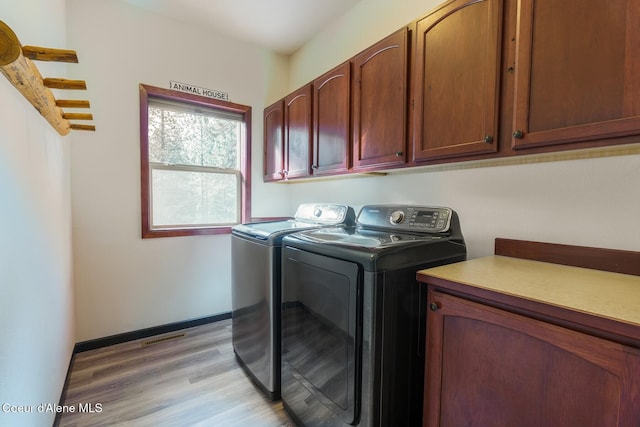 washroom with cabinet space, light wood finished floors, visible vents, baseboards, and washer and dryer