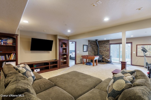 carpeted living area featuring baseboards, a wood stove, and recessed lighting