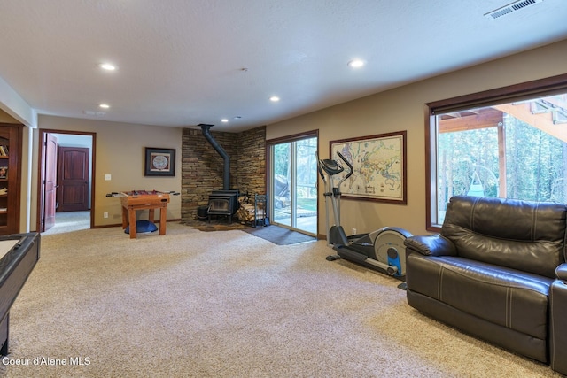 workout room with a wood stove, carpet floors, visible vents, and recessed lighting