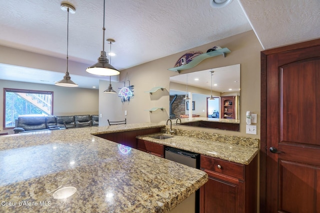 kitchen featuring light stone counters, hanging light fixtures, a sink, and a textured ceiling