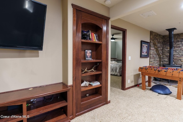 playroom featuring visible vents, carpet floors, a wood stove, and baseboards