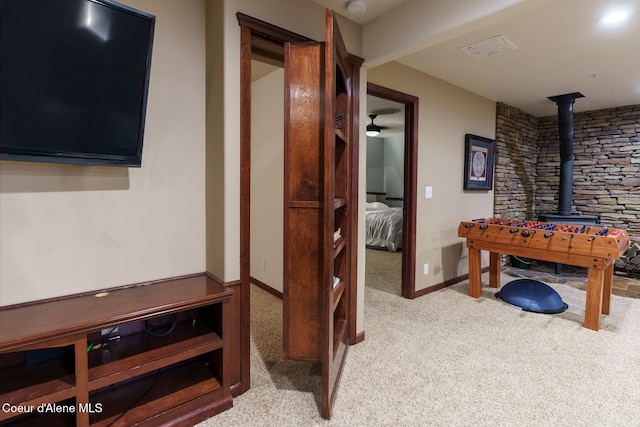 rec room featuring carpet floors, a wood stove, and baseboards