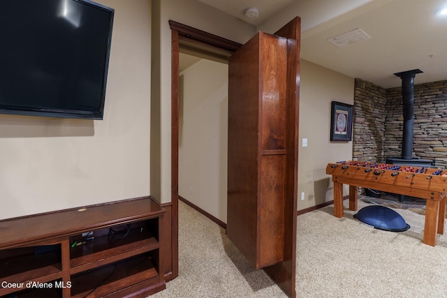 interior space featuring visible vents, carpet flooring, a wood stove, and baseboards