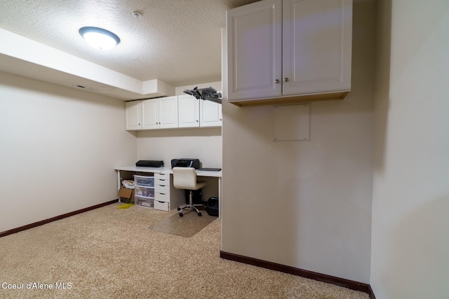 office space featuring a textured ceiling, light colored carpet, and baseboards