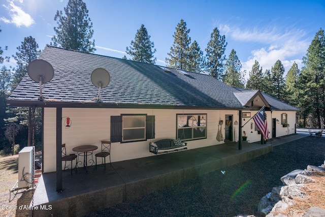 rear view of house with a patio area and a shingled roof