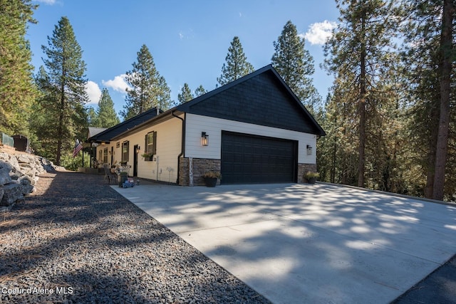 view of home's exterior featuring driveway, stone siding, and an attached garage