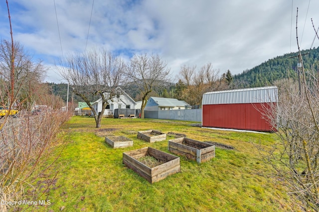 view of yard with a pole building, a vegetable garden, an outdoor structure, and fence