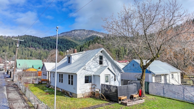 rear view of property with a forest view, a mountain view, metal roof, and a yard