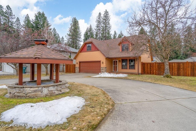 view of front of property featuring a garage, fence, a gazebo, stone siding, and a front yard