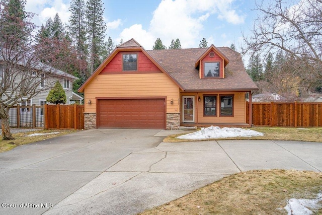 view of front facade featuring driveway, stone siding, and fence