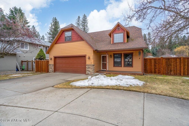 view of front of house featuring a garage, driveway, stone siding, and fence